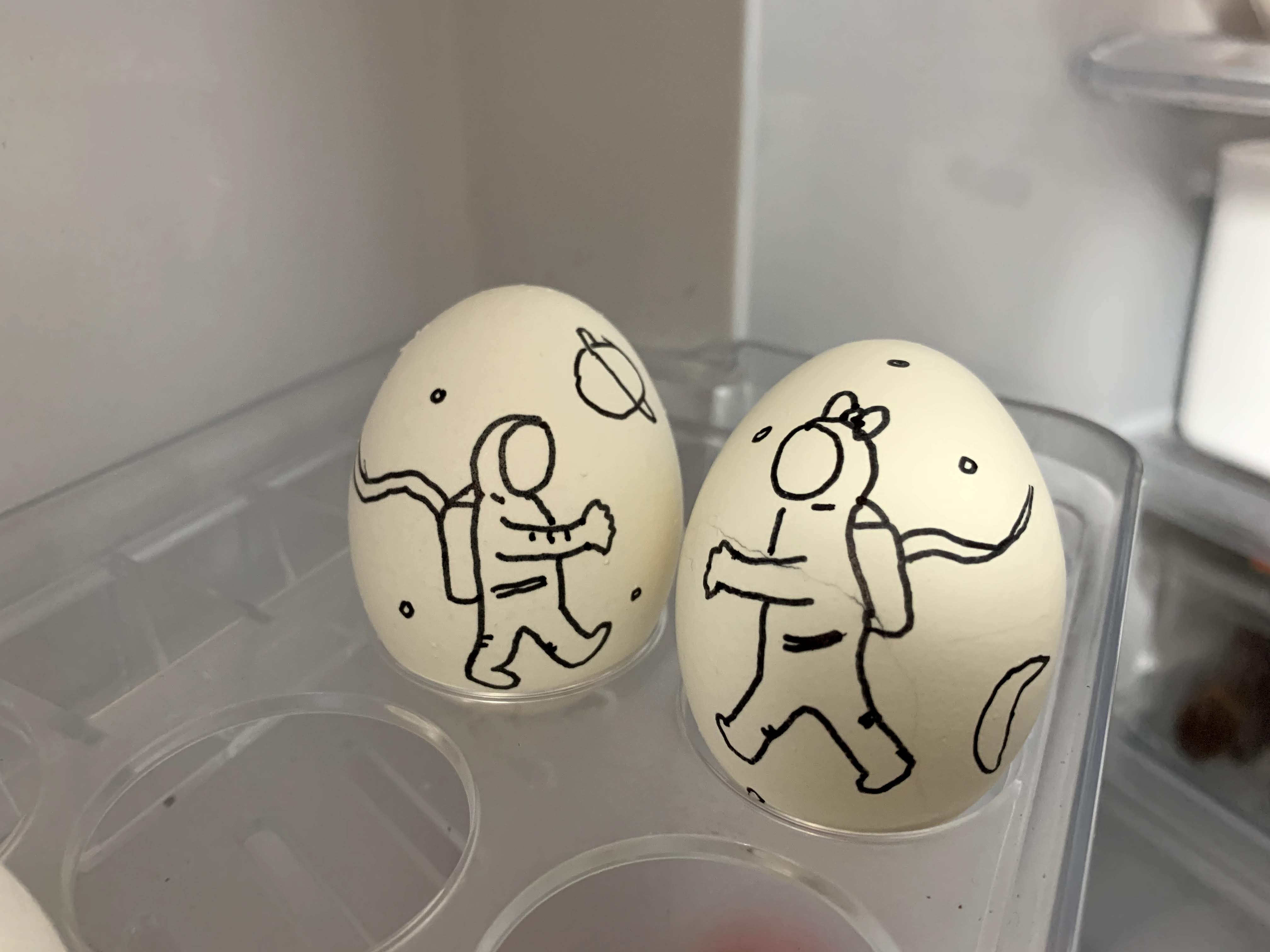 two boiled eggs with a picture of a boy and a girl astronaut