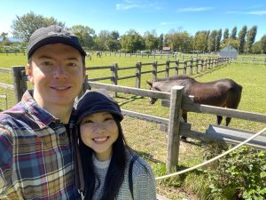 Megumi and Benjamin in front of a horse pen
